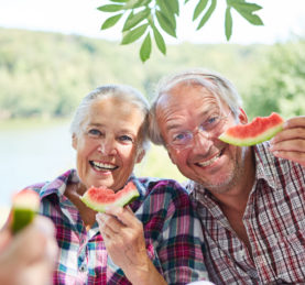 Glückliches Paar Senioren beim Melone essen zusammen auf einem Ausflug im Sommer